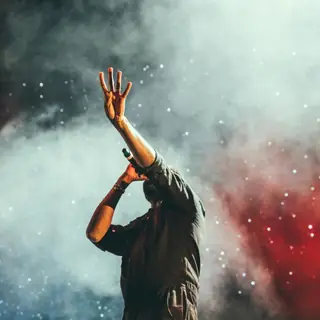 Performer with a raised hand in stage smoke